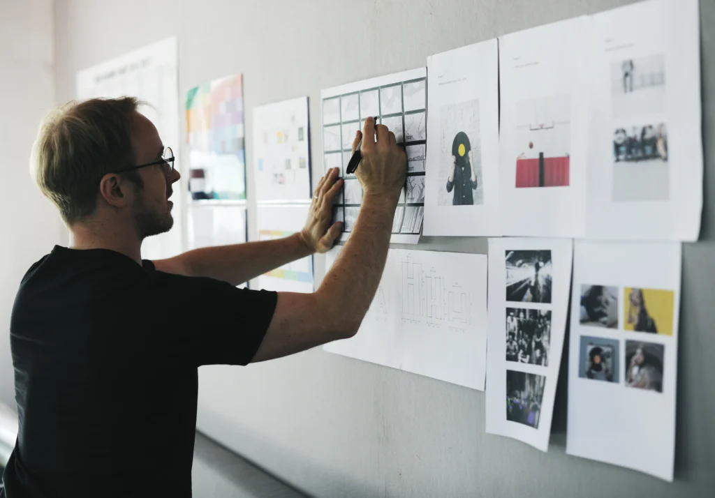 Diseñador frente a un moodboard escribiendo sobre él.