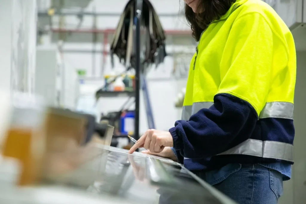 Mujer profesionista dentro de una fábrica industrial trabajando.